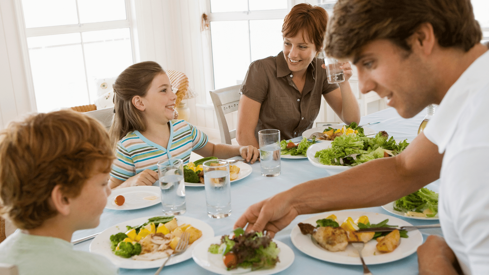 An image of a happy family of four eating a healthy meal